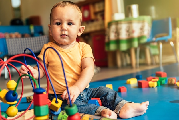 Photo joyeux bébé jouant avec des blocs de jouets à la maternelle.