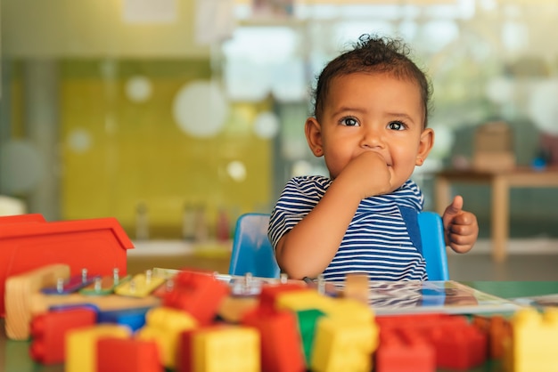 Photo joyeux bébé jouant avec des blocs de jouets à la maternelle.