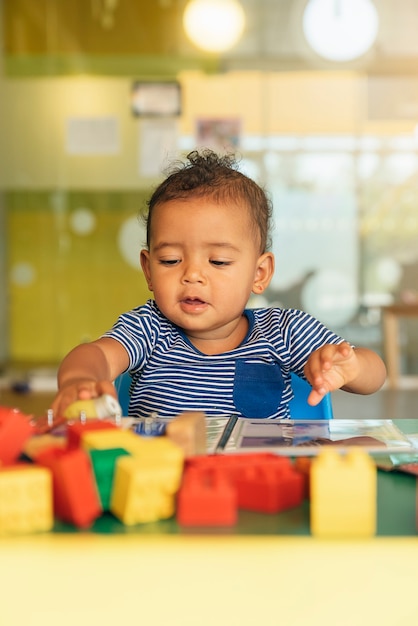 Photo joyeux bébé jouant avec des blocs de jouets à la maternelle.