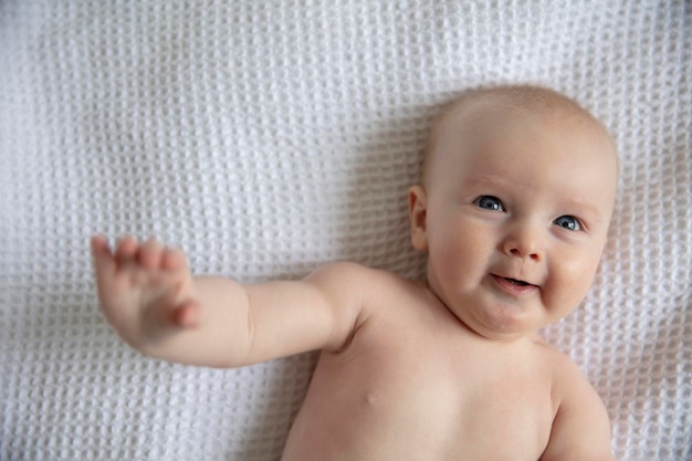 Joyeux bébé d'un mois allongé sur une couverture blanche en riant