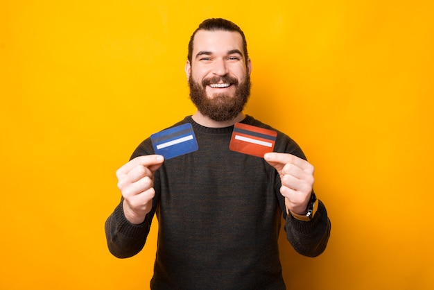 Photo joyeux bel homme barbu montrant deux cartes de crédit