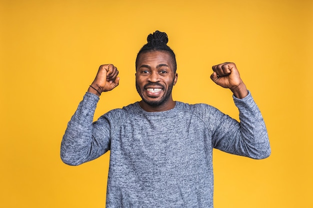 Joyeux bel homme noir afro-américain faisant un geste oui tout en étant excité à l'idée de gagner. Jeune fan extatique enracinant et exprimant son soutien. Concept de réussite isolé sur fond jaune.