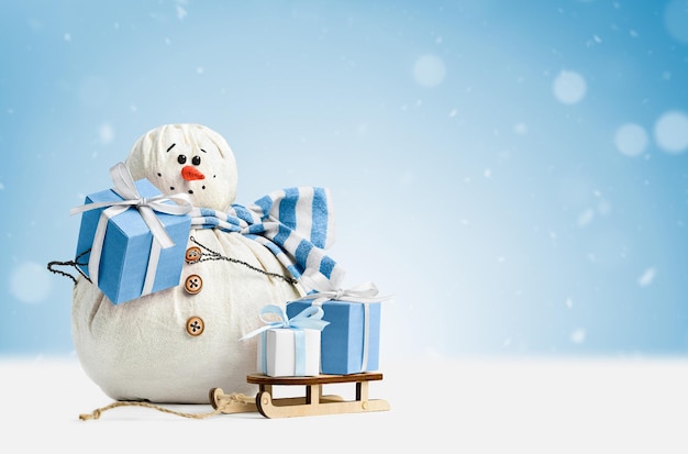 Joyeux bonhomme de neige avec des cadeaux sur fond bleu clair
