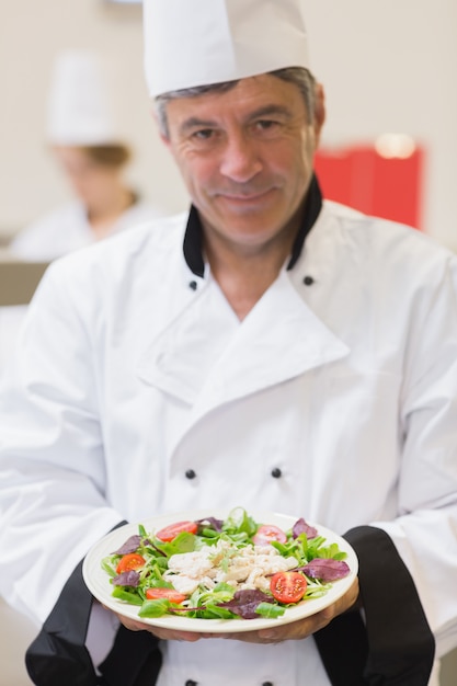 Joyeux chef présentant sa salade dans la cuisine