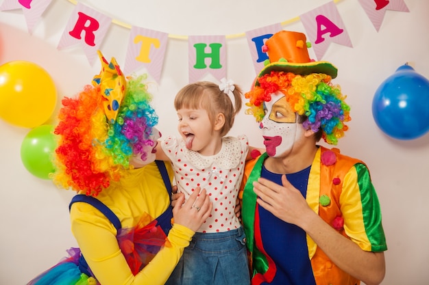 Joyeux clowns émotionnels en vacances avec une fille montrant leur langue