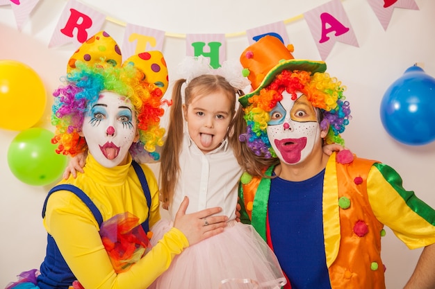 Joyeux clowns émotionnels en vacances avec une fille montrant leur langue