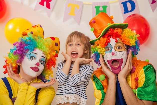 Joyeux clowns émotionnels en vacances avec une fille montrent des émotions