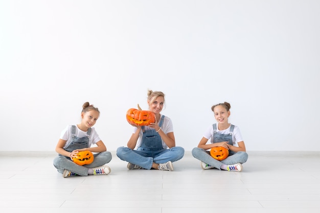 Joyeux concept d'halloween et de vacances - Une mère et ses filles avec des citrouilles. Famille heureuse se préparant pour Halloween.