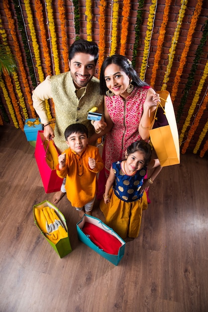 Joyeux concept de magasinage du festival de la famille indienne - tenant des sacs en papier et montrant une carte de débit ou de crédit