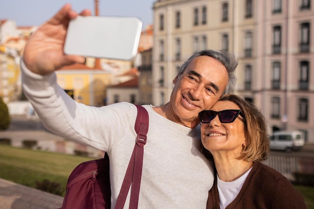 Joyeux conjoints seniors faisant selfie sur téléphone portable debout à l'extérieur