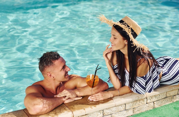 Joyeux couple ou amis ensemble dans la piscine en vacances