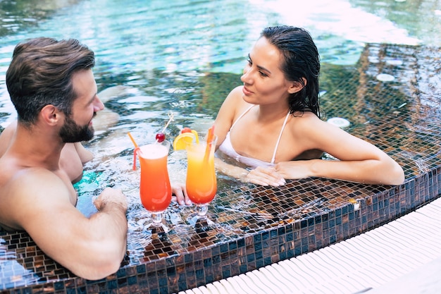 Joyeux couple amoureux se repose dans une piscine pendant les vacances d'été.