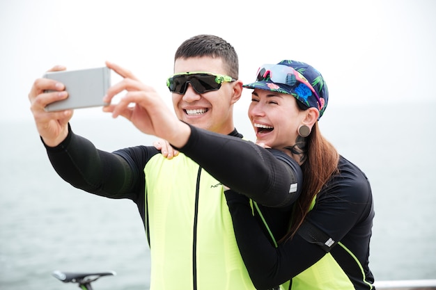 Joyeux couple cyclistes faisant une photo de selfie à l'extérieur