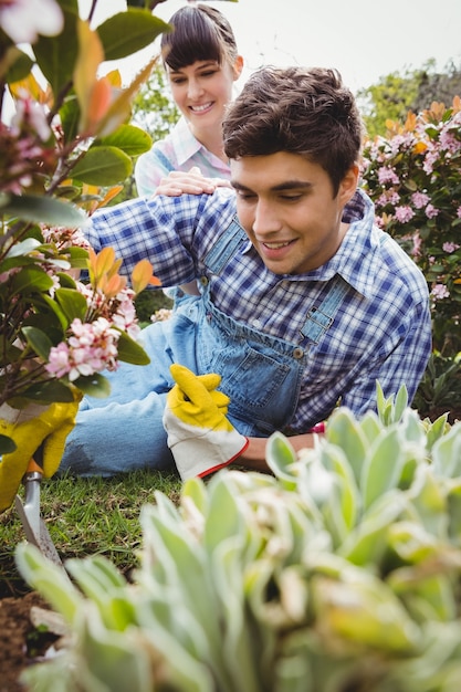 Joyeux couple entretenant des plantes dans le jardin