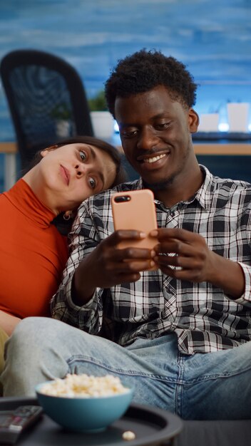 Joyeux couple interracial prenant des selfies avec un smartphone