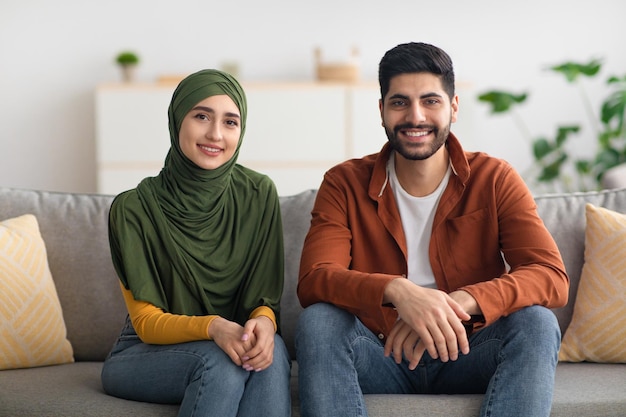 Joyeux couple marié moyen-oriental assis sur un canapé à la maison