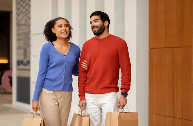 Joyeux couple mixte faisant du shopping ensemble en profitant du week-end à l'extérieur