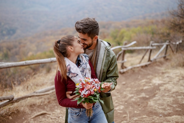 Joyeux couple multiculturel mignon habillé décontracté debout dans la nature et les caresses.