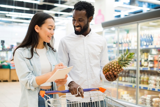 Joyeux couple multiracial, achat de biens en supermarché
