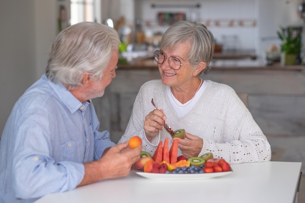 Photo joyeux couple de personnes âgées caucasien prenant son petit déjeuner à la maison avec des fruits frais de saison concept de saine alimentation