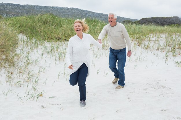 Joyeux couple de personnes âgées en cours d&#39;exécution à la plage