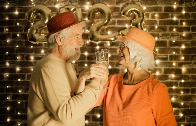 Joyeux couple de personnes âgées floues tenant des flûtes à champagne faisant la fête la nuit Mode de vie de bonheur pour les retraités matures attendant le nouvel an 2023