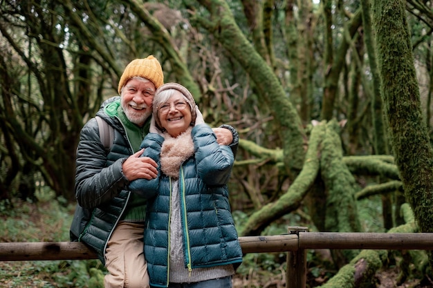 Joyeux couple de personnes âgées profitant de la nature en plein air dans une forêt de montagne avec des troncs couverts de mousse Joyeux couple de personnes âgées voyageant ensemble dans le parc national de Garajonay de La Gomera