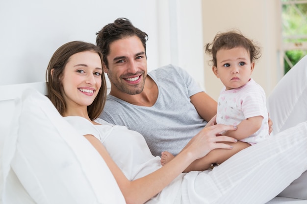 Joyeux couple avec sa fille au lit