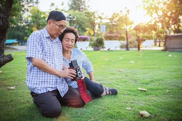 Joyeux couple senior asiatique profitant de la photographie dans le parc avec un appareil photo rétro