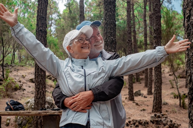 Joyeux couple senior s'embrassant en profitant d'une randonnée en montagne dans les bois, appréciant la nature et la liberté