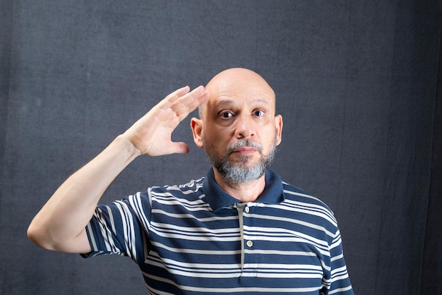 Joyeux drôle jeune homme d'affaires barbu en chemise rayée classique debout faisant des gestes de la main isolé sur fond gris portrait en studio réalisation concept de richesse de carrière