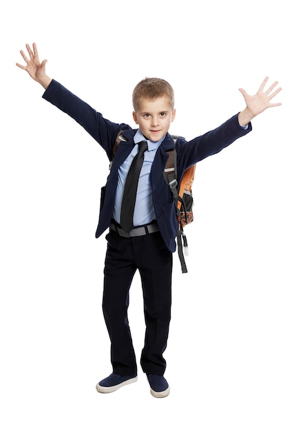 Joyeux écolier en uniforme avec un sac à dos avec ses mains.