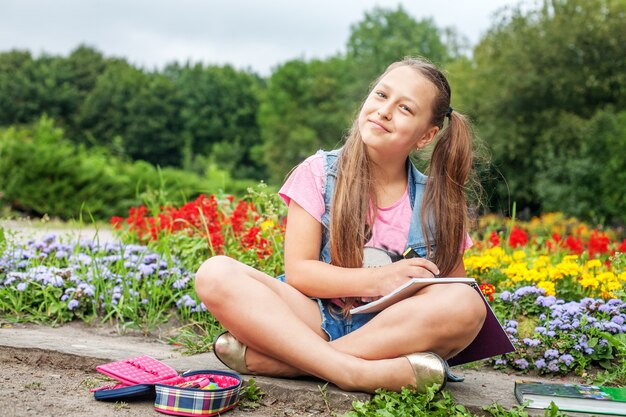 Joyeux élève écrit dans un cahier. Fille. Le concept de chil