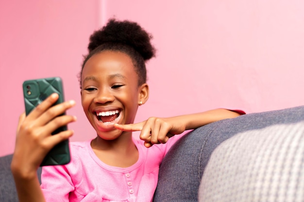 Photo joyeux enfant africain avec un grand sourire tenant joyeusement un téléphone portable