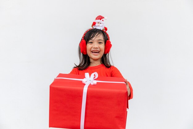 Joyeux enfant asiatique au chapeau rouge de Santa tenant des cadeaux de Noël. Temps de Noël.sur fond blanc.