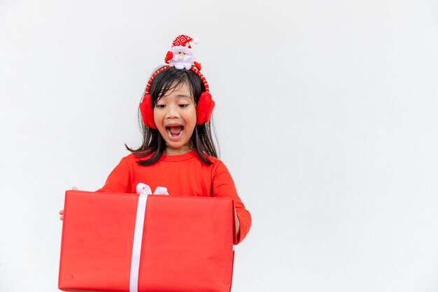 Joyeux enfant asiatique au chapeau rouge de Santa tenant des cadeaux de Noël. Temps de Noël.sur fond blanc.