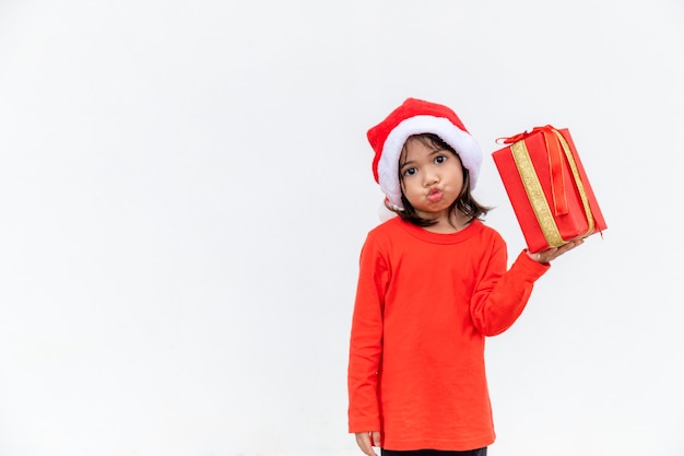 Joyeux enfant asiatique au chapeau rouge de Santa tenant des cadeaux de Noël. Temps de Noël.sur fond blanc.