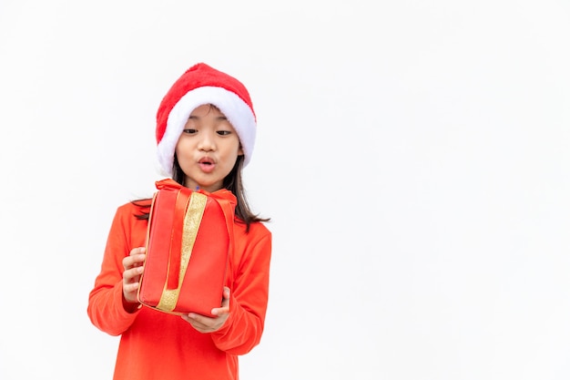 Joyeux enfant asiatique au chapeau rouge de Santa tenant des cadeaux de Noël. Temps de Noël.sur fond blanc.