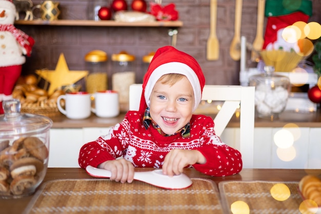 Joyeux enfant en bas âge fêter noël dans la cuisine à la maison joyeux noël et bonne année