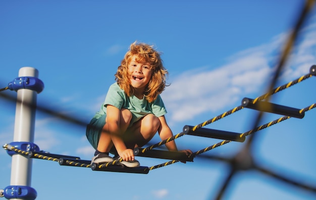 Joyeux enfant garçon s'amusant sur l'aire de jeux en plein air Cute boy monte l'échelle sur l'aire de jeux Chi