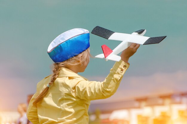 Joyeux enfant jouant avec un avion jouet sur fond de ciel bleu d'été.