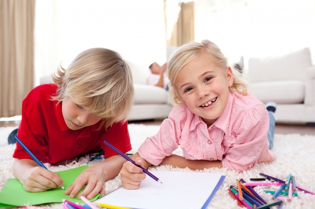 Joyeux enfants dessin allongé sur le sol