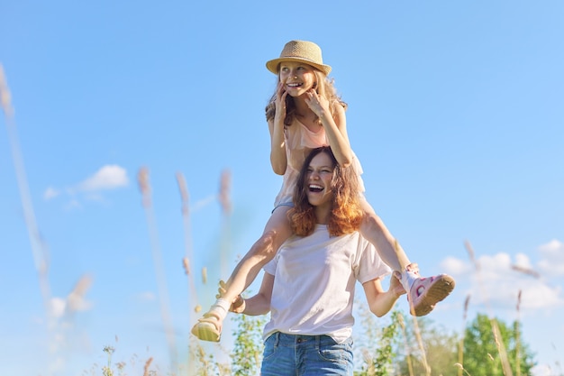 Joyeux enfants riant jouant dans le pré, deux sœurs s'amusant dans la nature