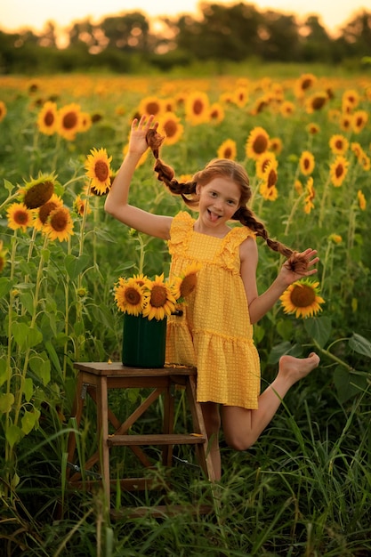 Joyeux été à la campagne joyeuse fille coquine aux cheveux roux avec des nattes sur un champ de tournesols au coucher du soleil