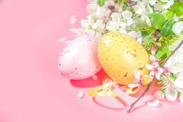 Joyeux fond de carte de voeux de vacances de printemps de Pâques avec des oeufs colorés de Pâques, des nids d'oiseaux décoratifs et des fleurs de jardin de printemps en fleurs, un espace de copie flatlay sur fond rose de haute couleur