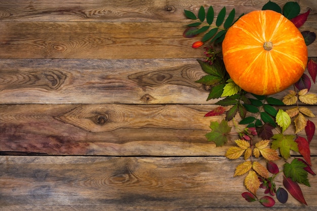 Joyeux fond de Thanksgiving avec des feuilles de citrouille et d'automne sur le côté gauche de la table en bois rustique. Décor d'automne avec légumes de saison, espace copie