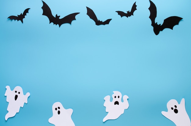 Joyeux fond de vacances d'Halloween avec du papier kraft sous forme de fantômes et de chauves-souris sur bleu. Fête d'Halloween avec décoration.