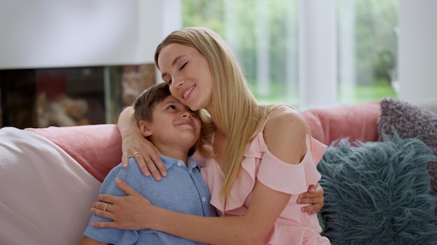 Joyeux garçon embrassant sa mère Femme souriante embrassant son fils à la maison