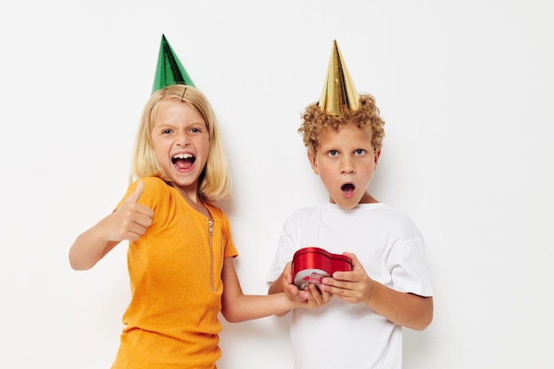 Joyeux garçon avec une fille avec des chapeaux cadeau anniversaire vacances