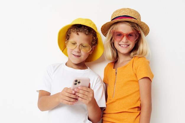 Joyeux garçon et fille dans des lunettes à la mode chapeaux selfie posant